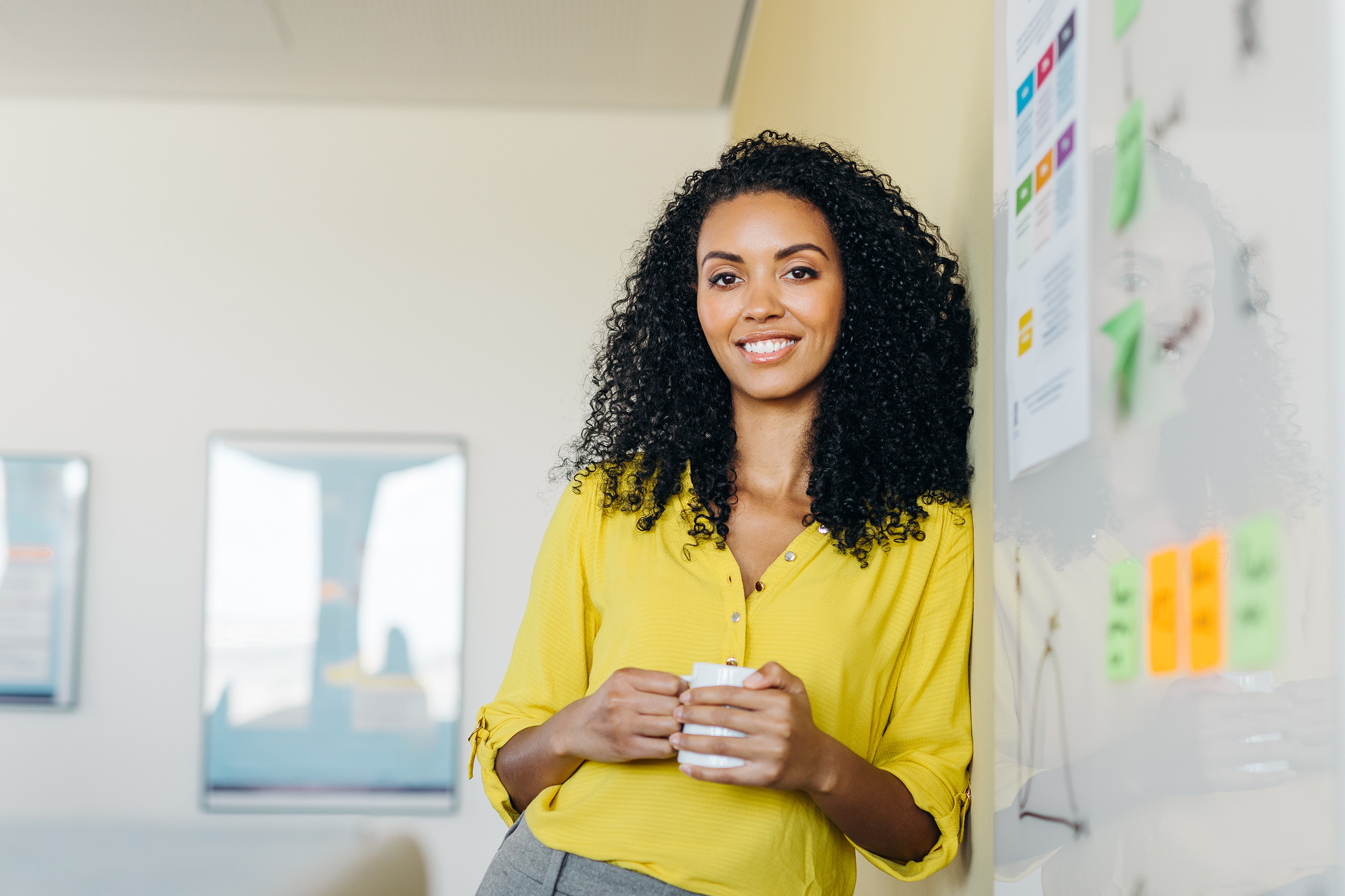 Moderner Business-Lifestyle: Frau mit Kaffeetasse in heller, minimalistischer Büroumgebung mit weichem Lichteinfall