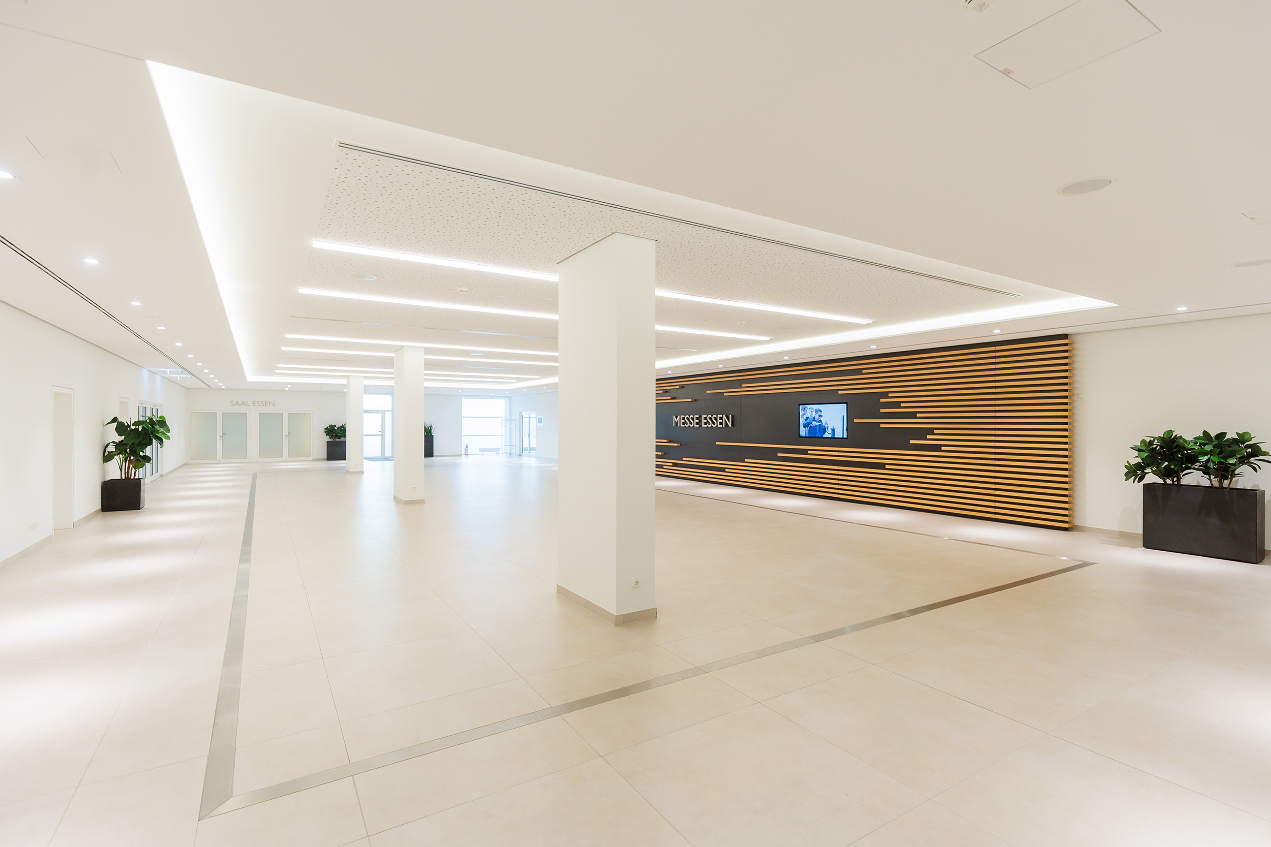 Moderne Architekturfotografie des lichtdurchfluteten Foyers der Messe Essen mit Fokus auf symmetrische Linienführung, minimalistisches Design und warmes Lichtkonzept